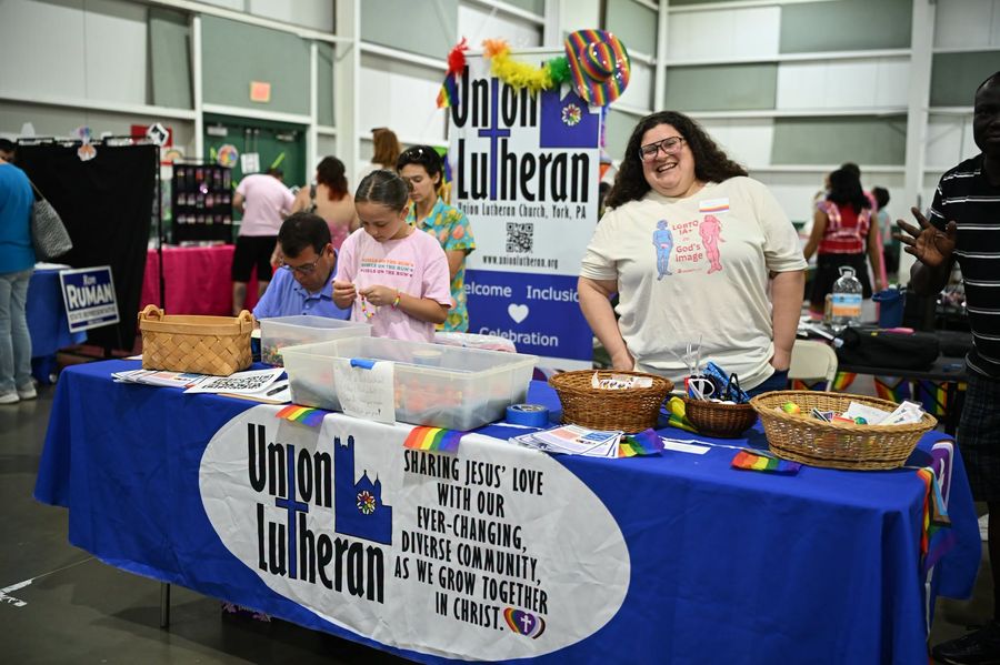 A volunteer smiling at the Union Lutheran Church table at a Pride event