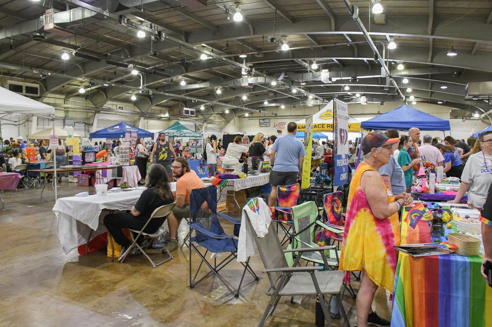 Vendors and visitors gathered at tables and tents inside an indoor York County Pride event